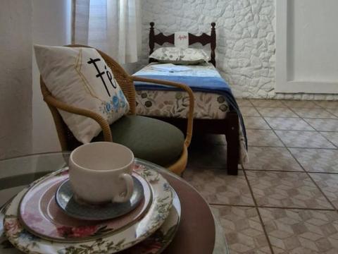 Quarto individual com cama, poltrona e mesa de apoio