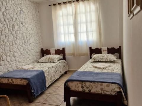 Quarto com duas camas de solteiro e cortinas claras