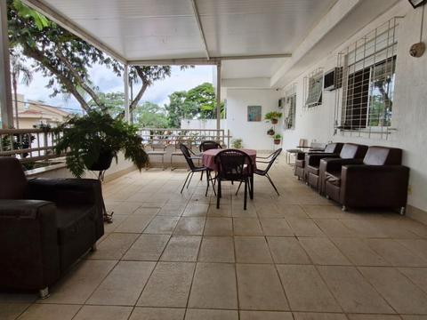 Varanda ampla com sofás e mesa, com vista para o jardim