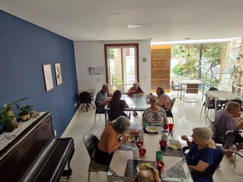 Residentes ao redor de uma mesa, perto do piano