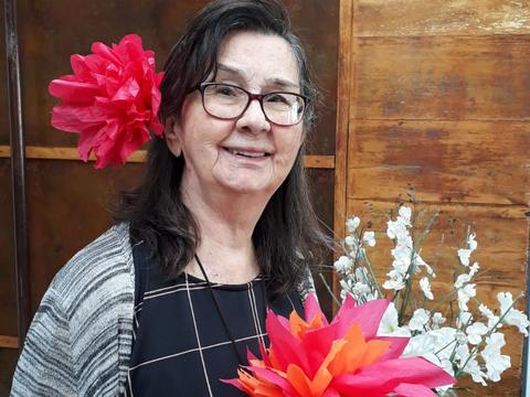 Residente sorrindo, com uma grande flor vermelha