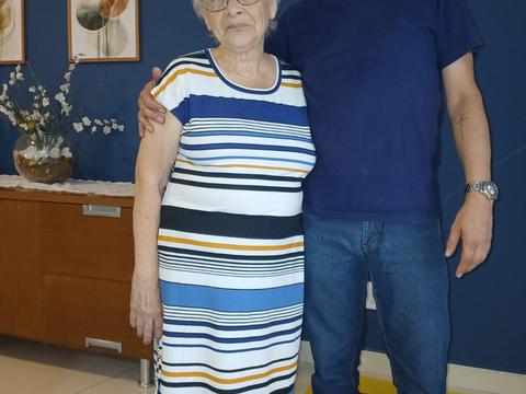 Residente e familiar posando juntos em sala com parede azul